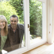 Ein Paar schaut durch ein Fenster in eine freie Immobilie.